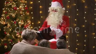 圣诞老人为家人<strong>读书</strong>。 母亲和孩子们坐在室内，靠近装饰<strong>好</strong>的圣诞树和灯-圣诞快乐